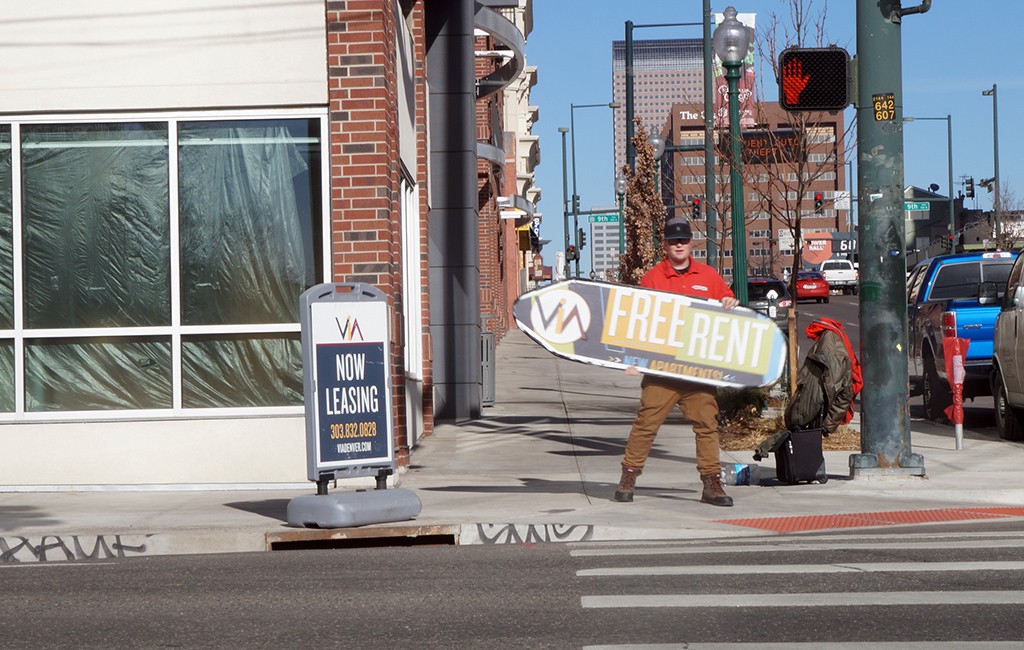 A sign spinner outside of an apartment building in Denver advertises a rent discount. (Aaron Kremer)