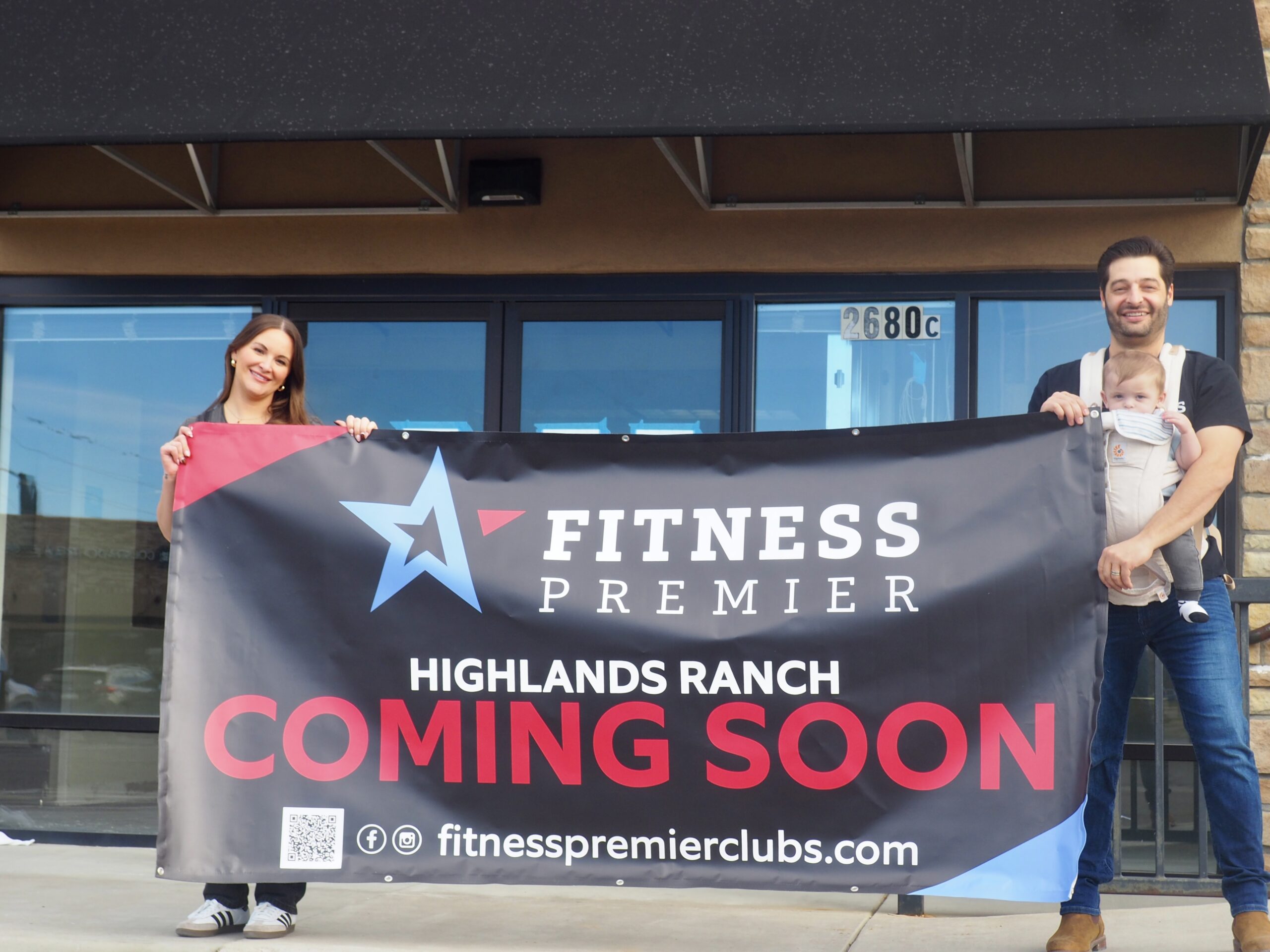 Brooke Aguilera, left, stands with her husband Carlos and their baby Rowan outside the future storefront of their gym.